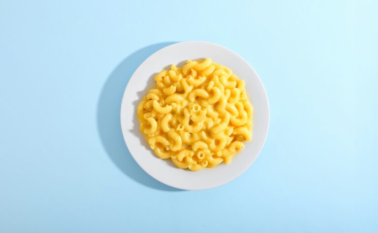 Bowl of macaroni and cheese on a blue background
